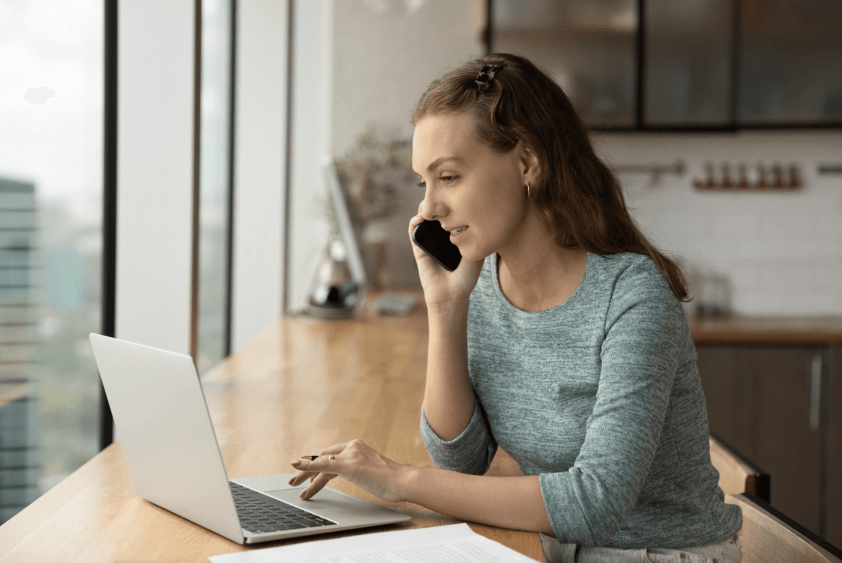 Woman talks on phone while looking at her laptop