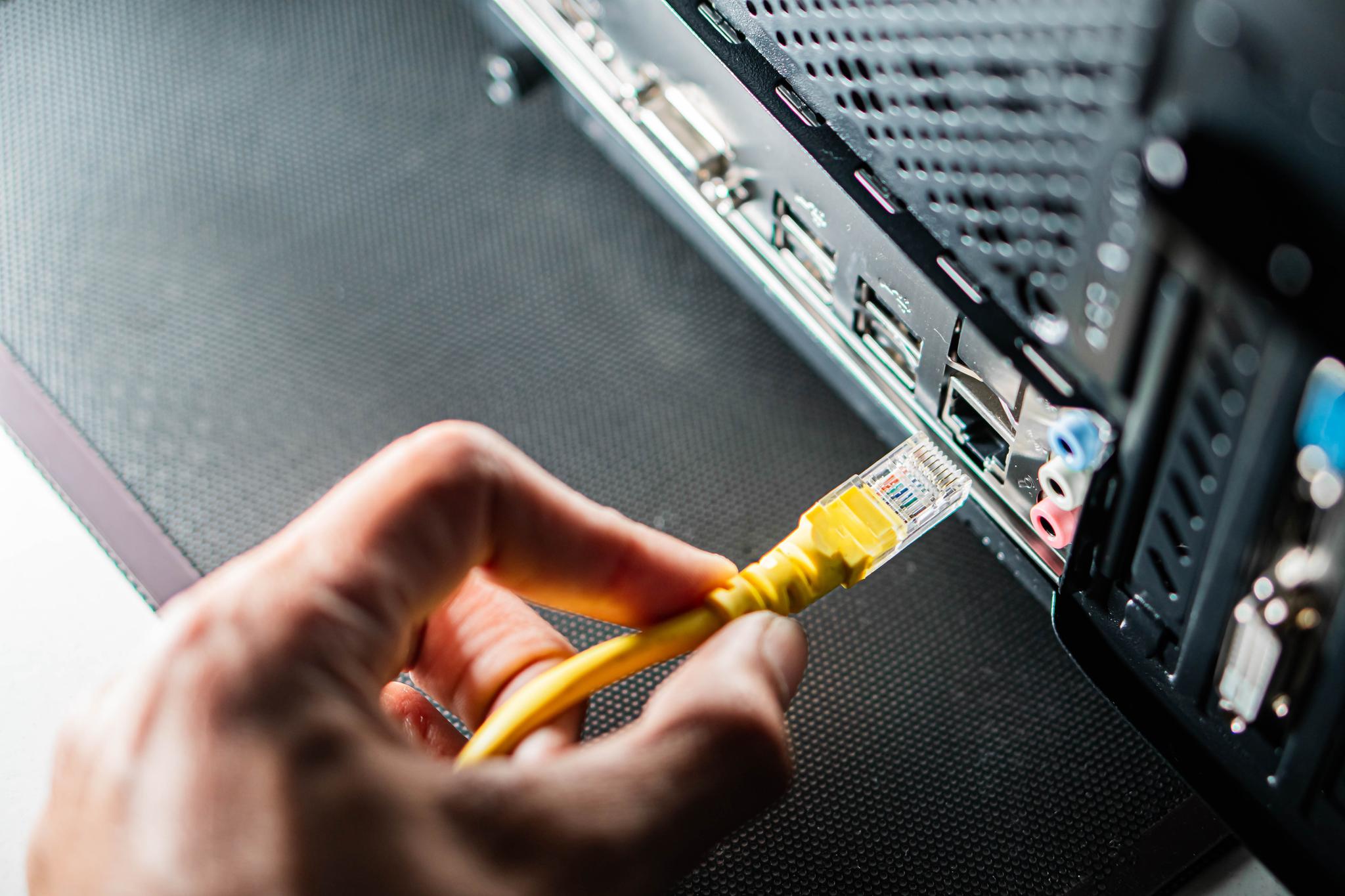 Hand plugs in ethernet cord to back of computer