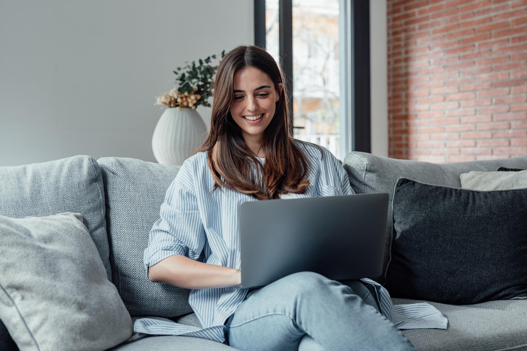 A person sitting on a couch, using a computer