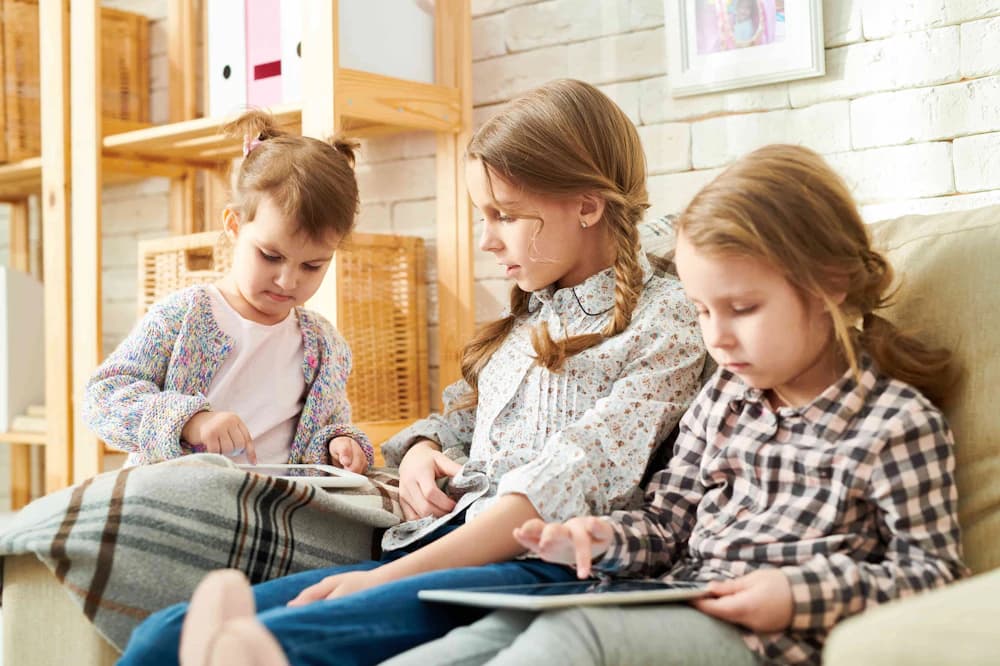 Three young children use tablets to enjoy online activities