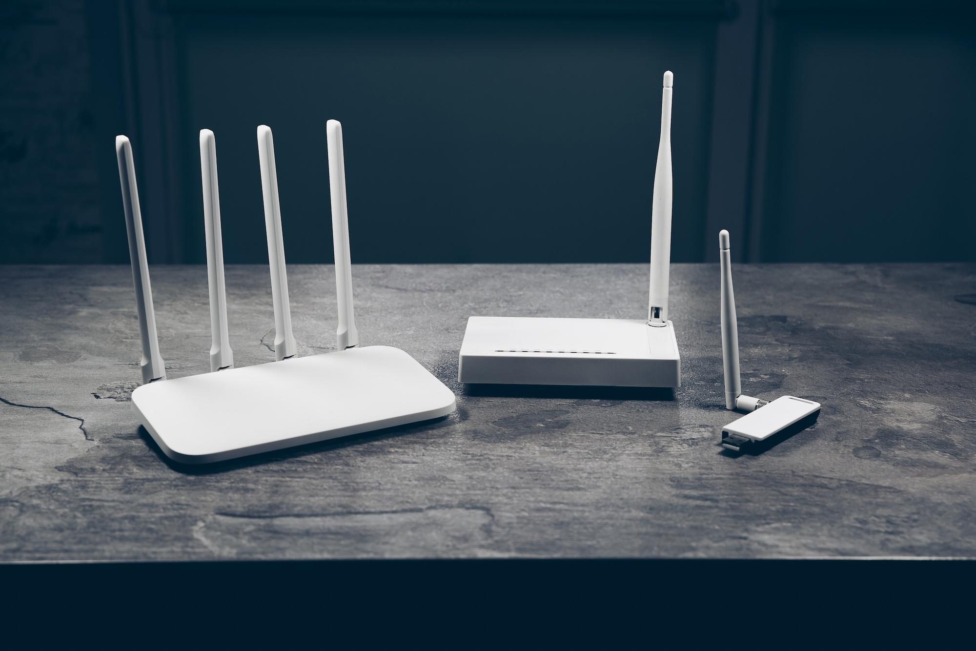 Three different types of Wi-Fi routers on a dark gray table