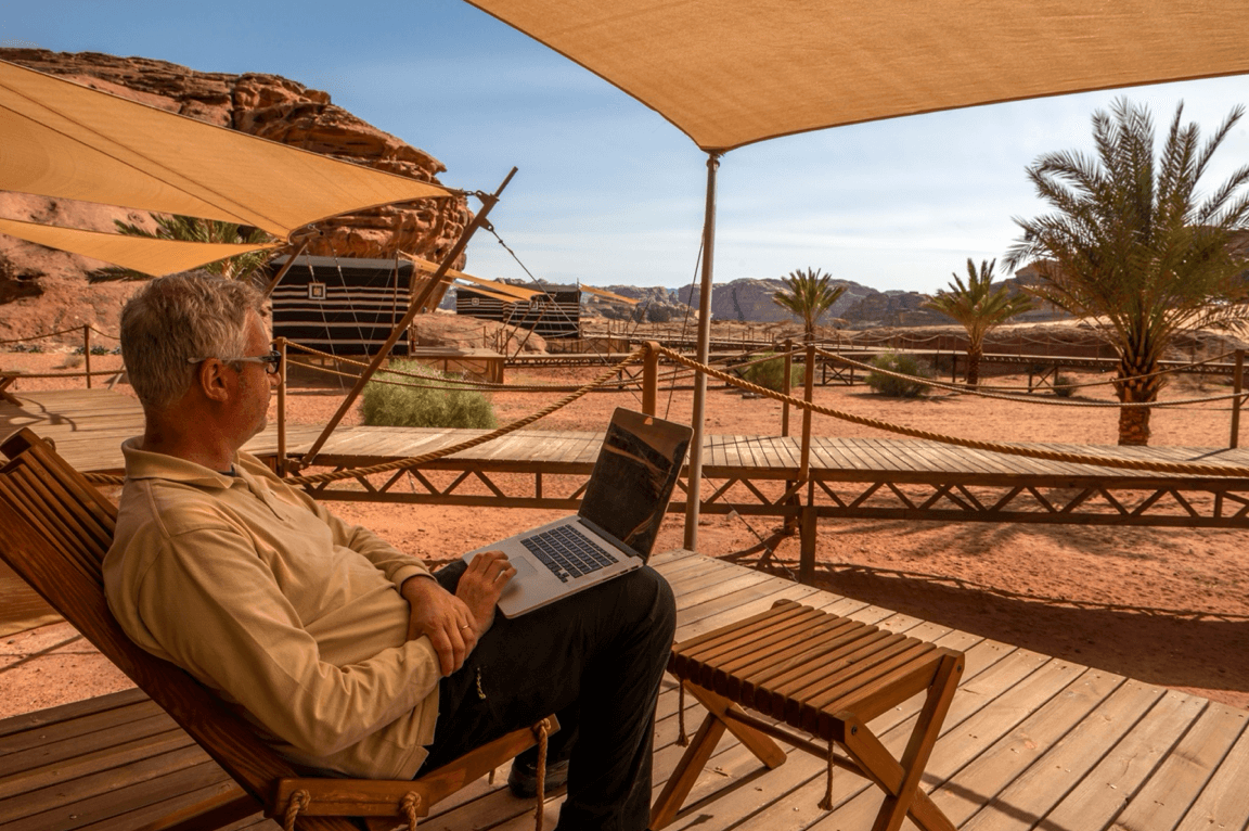 Man works on laptop outside of his remote desert home
