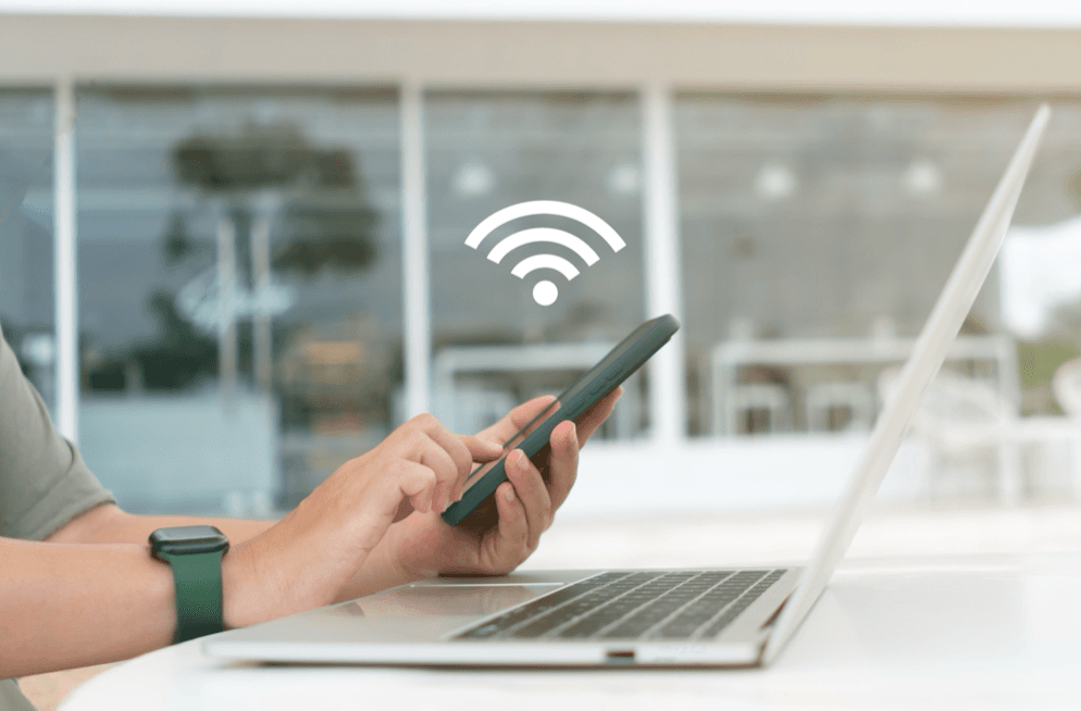 Wi-Fi signal hovering above a smart phone and laptop connecting via a hotspot