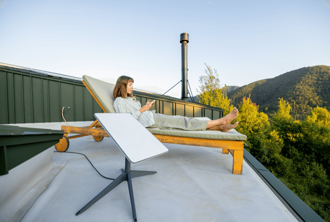 A woman uses satellite internet while enjoying the serene atmosphere of a mountain cabin.