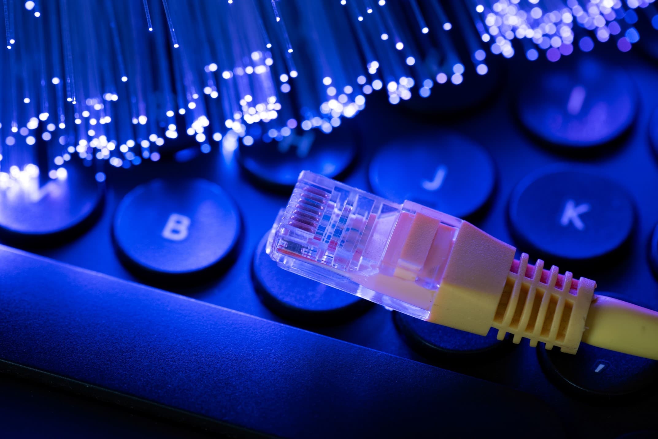 Fiber optic internet cables and ethernet cord on top of a keyboard
