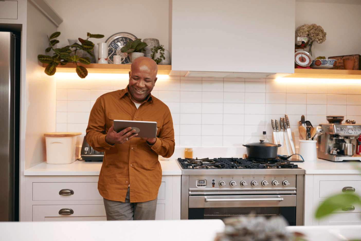 Smiling man looks at his tablet while standing in a modern kitchen