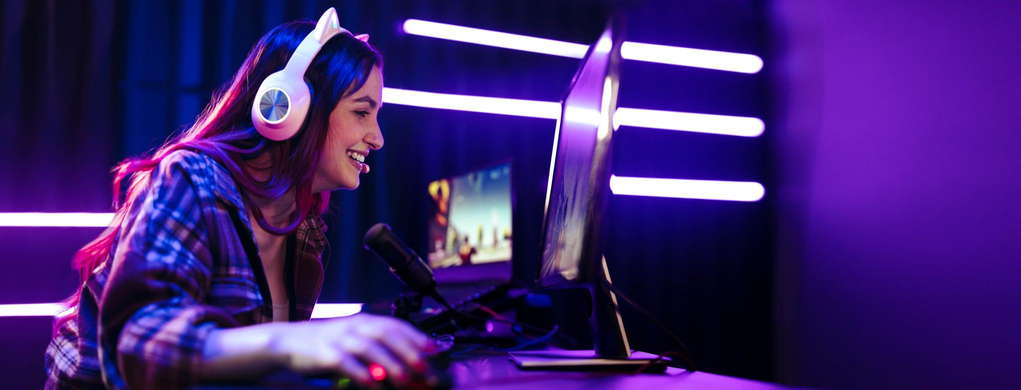 Girl gamer smiles while she plays a game on a computer