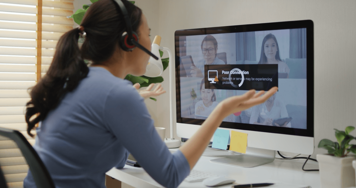 Frustrated woman puts hands up during a video call on a computer with low bandwidth