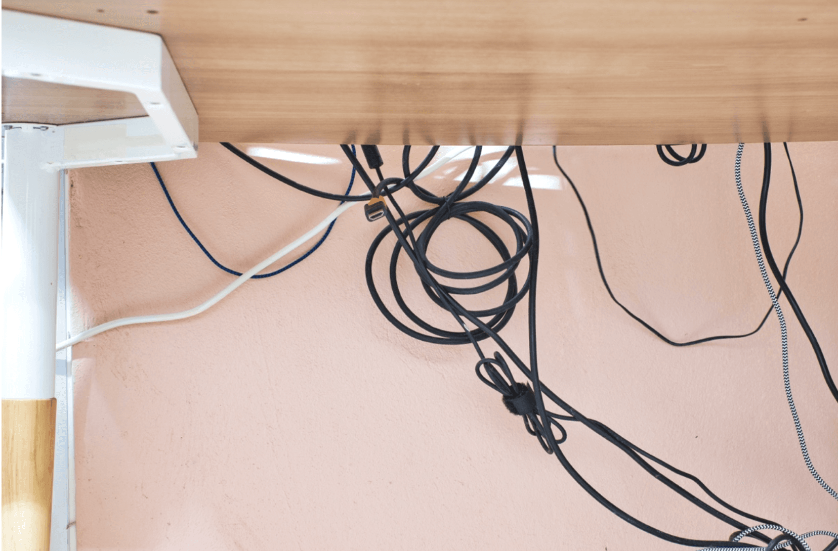 Messy internet and electric cables tangled underneath a desk