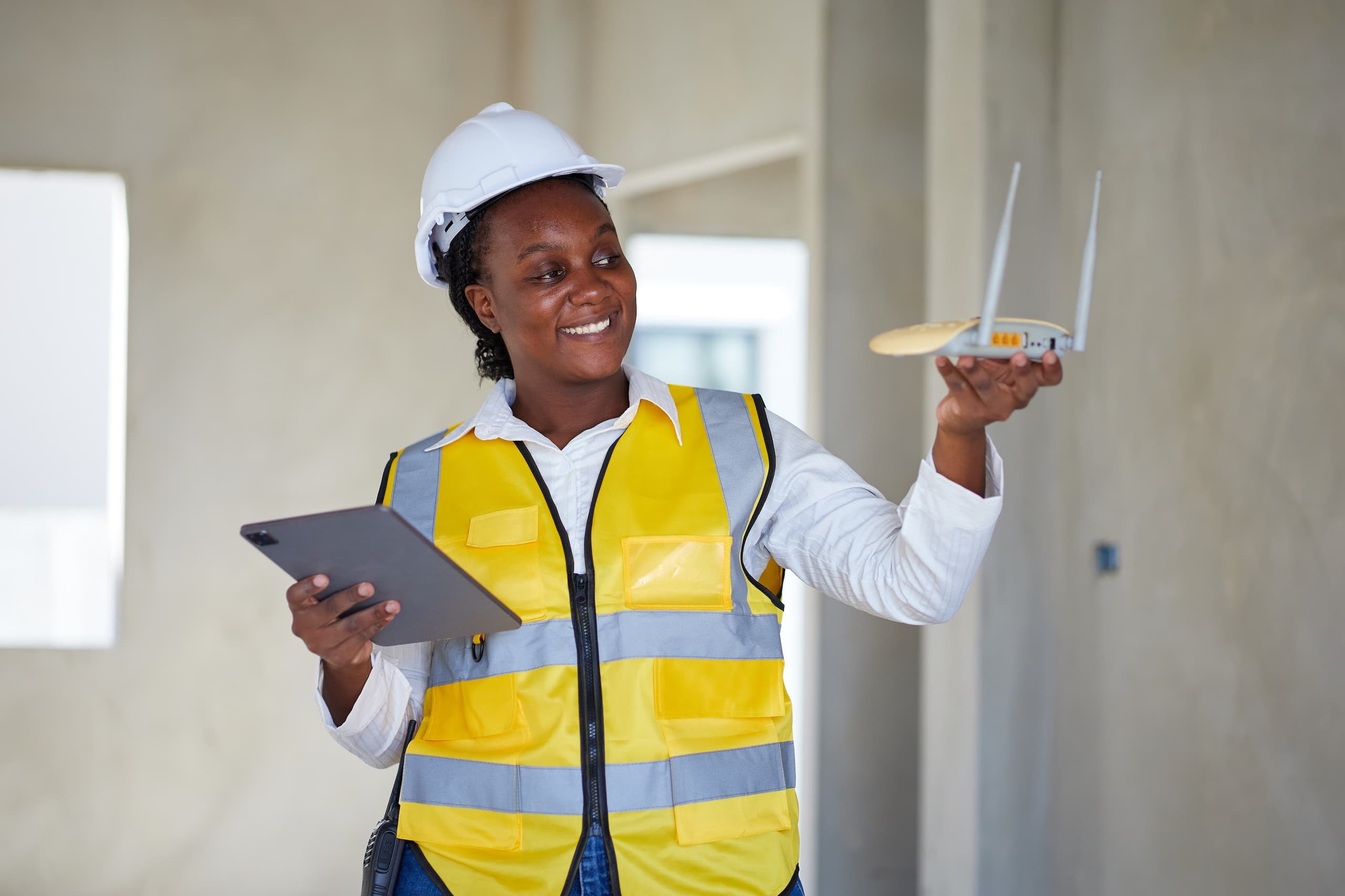 blog/Internet technician holds a tablet in one hand and router in the other