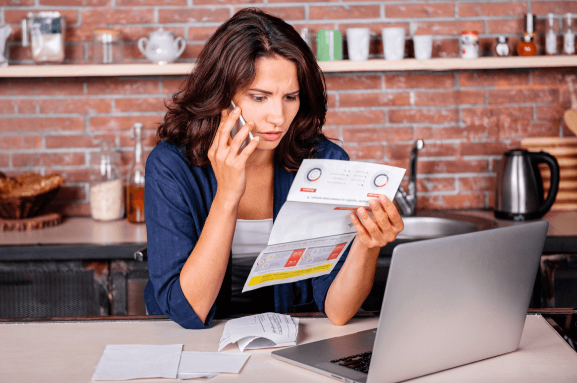 blog/Concerned woman looks at internet bill while on the phone with laptop open.png