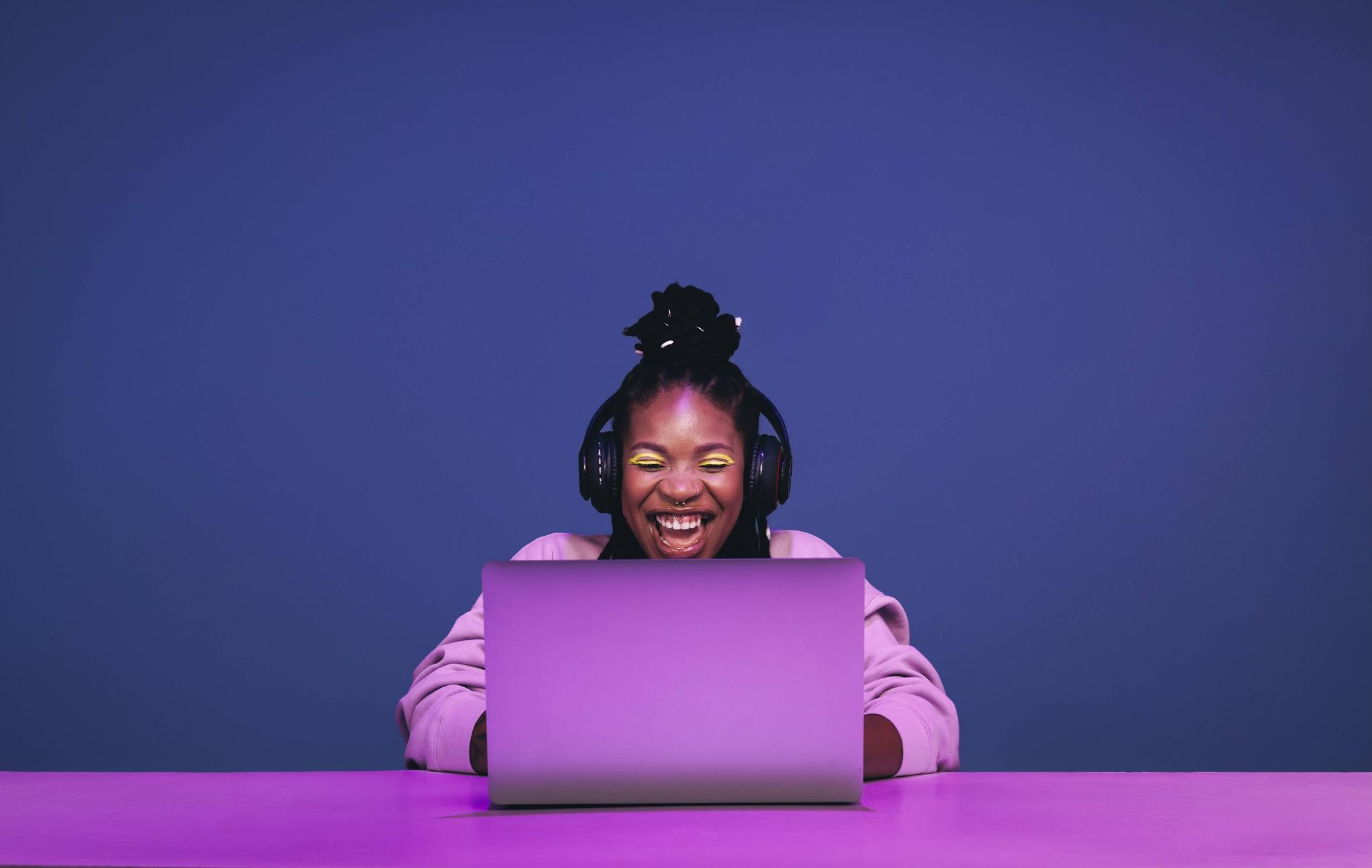 Cheerful woman smiles while gaming on a purple laptop