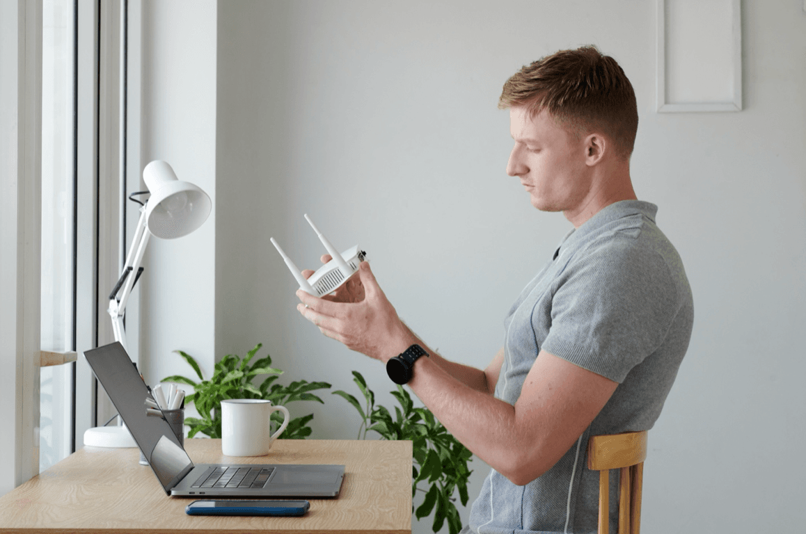 Man sits at home desk with router in his hands