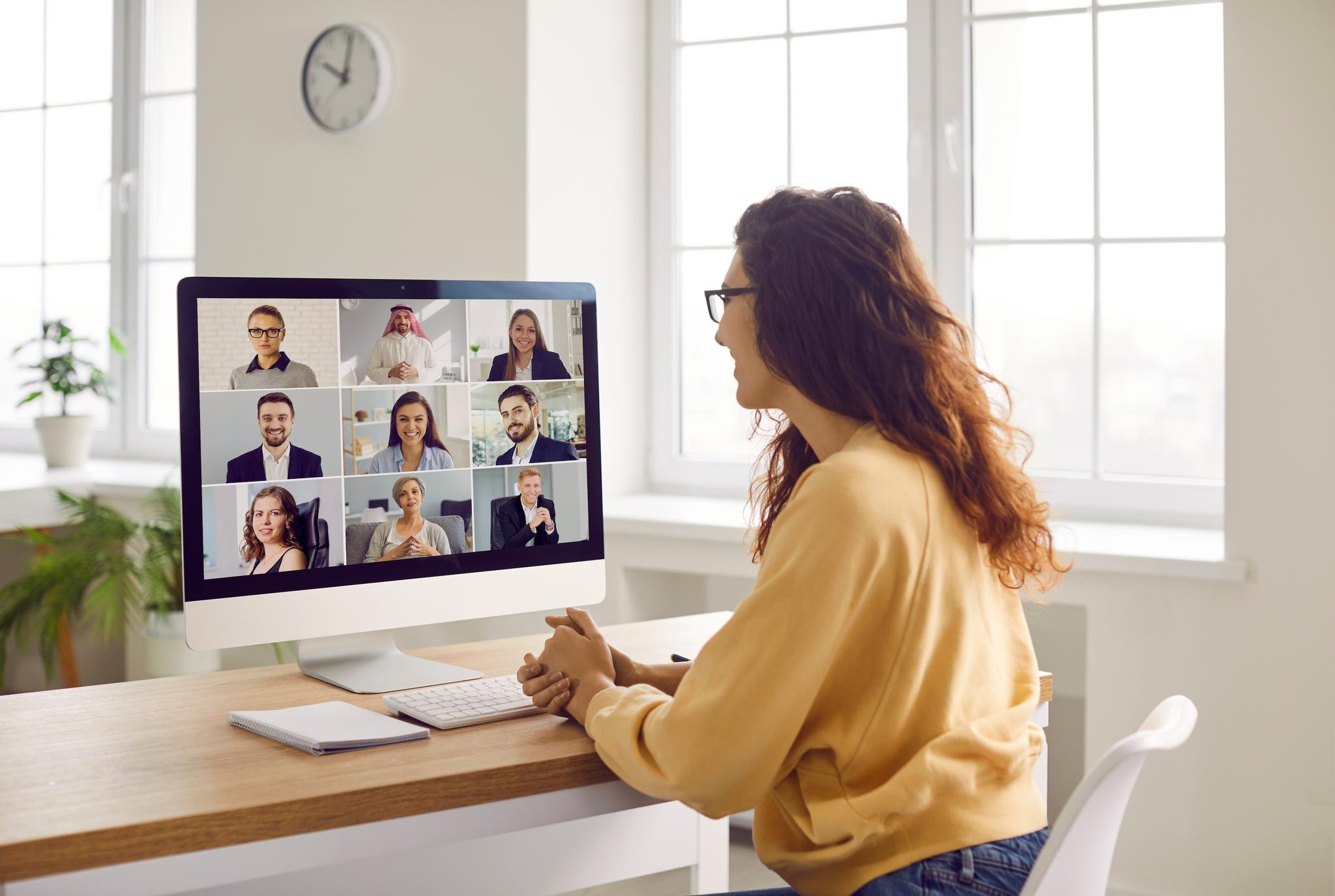 Woman working from home attends a video conference with several other coworkers