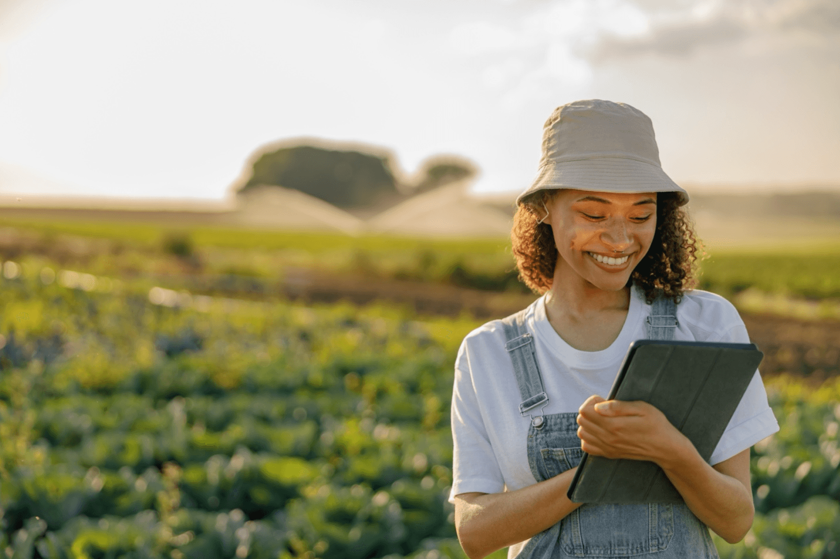 Smiling woman checks her tablet while standing in a field