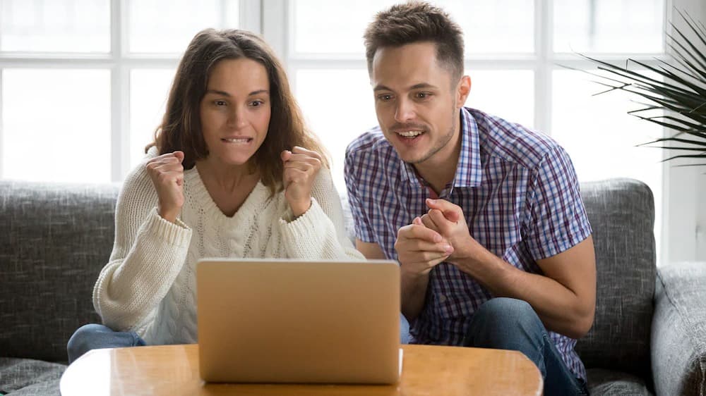 Young man and woman watch football by streaming on a laptop