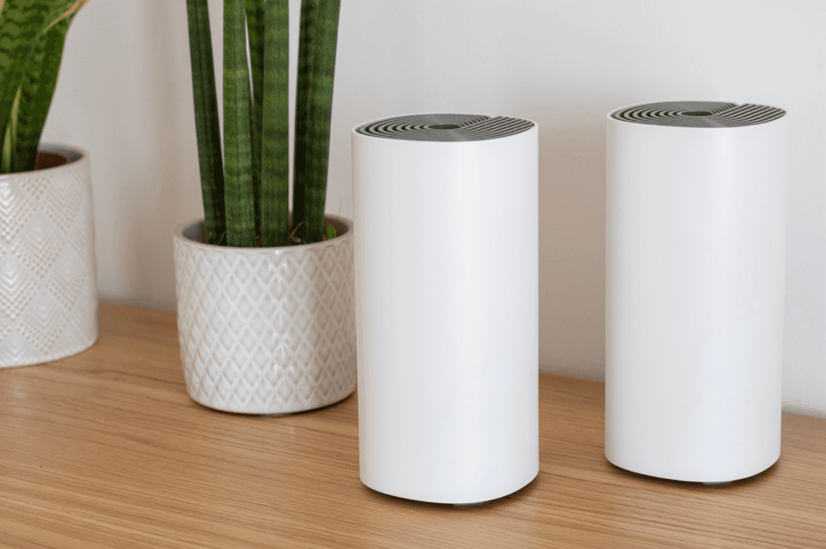 Mesh Wi-Fi network devices on a table next to a plant