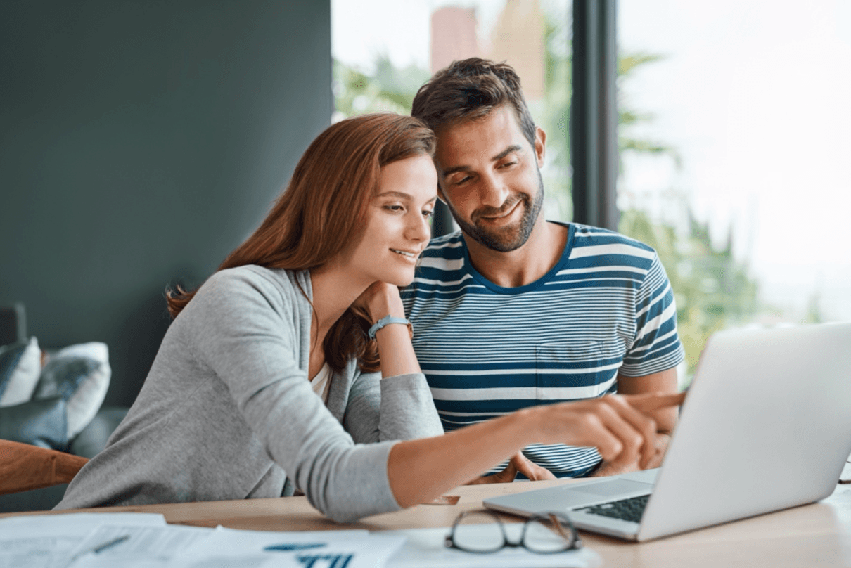Couple at the kitchen table look at a laptop together