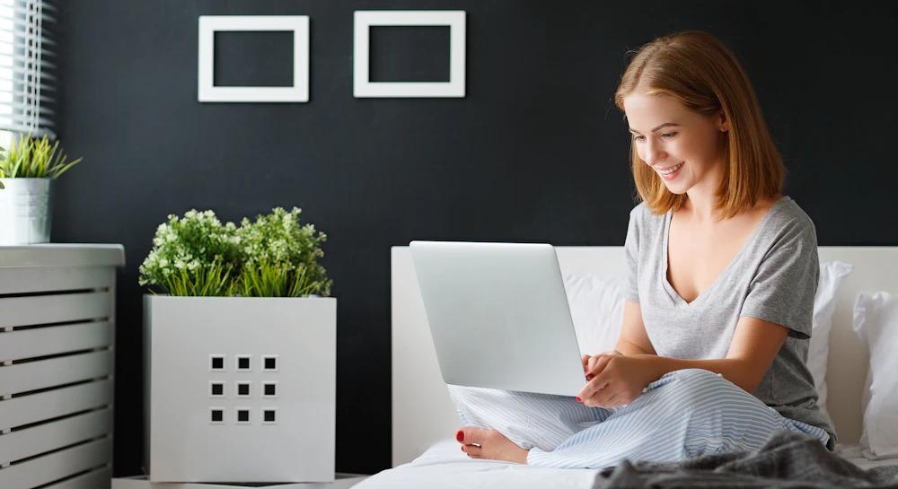 Woman uses laptop in bed.