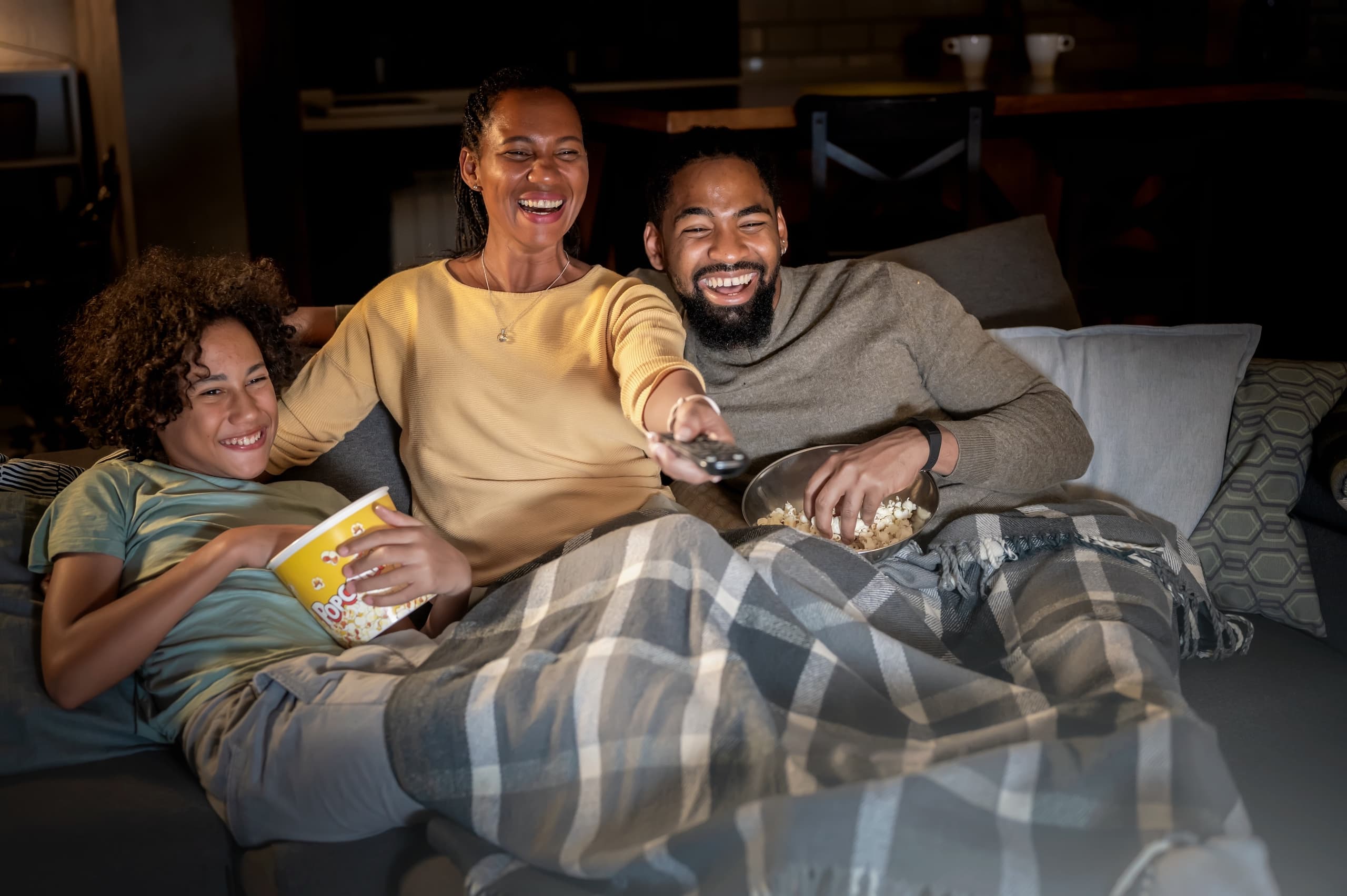 blog/Happy family smiles and eats popcorn on the couch while watching a movie together