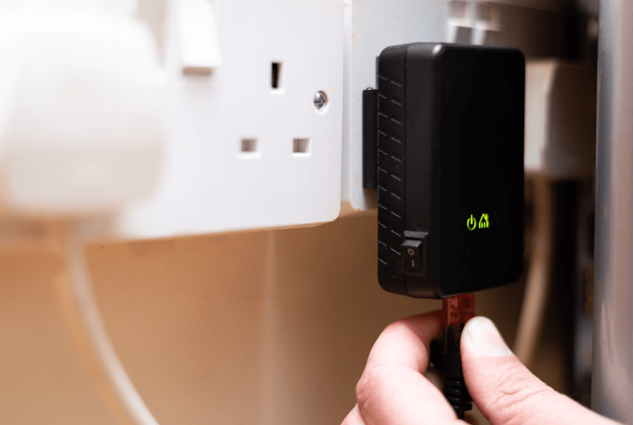 Hand plugs in network powerline adapter into outlet