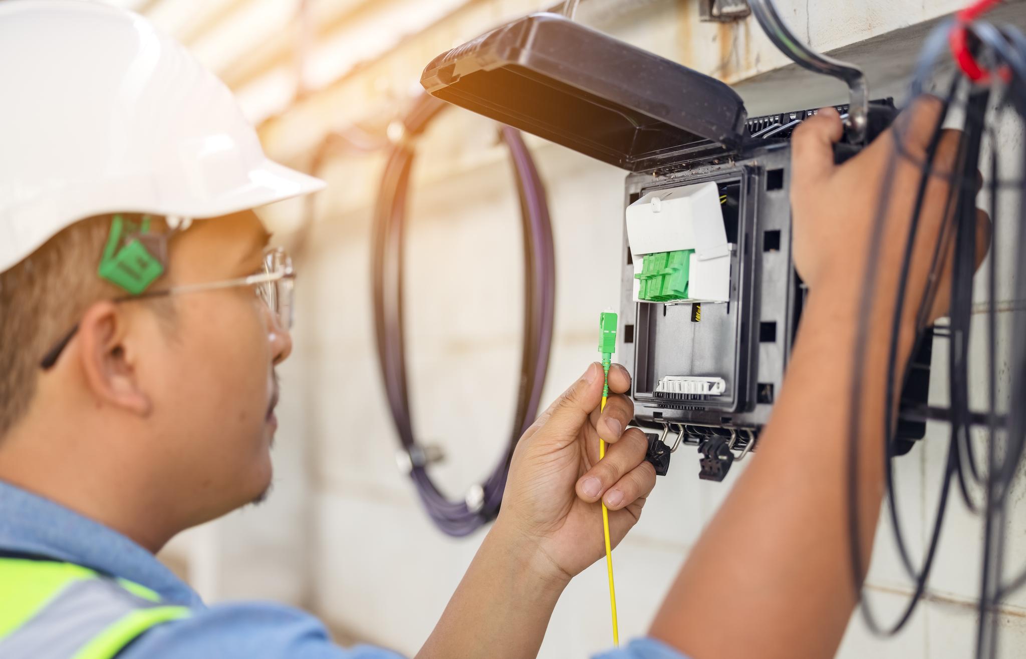 An internet technician installing a fiber-optic connection by opening a fiber-optic connector.