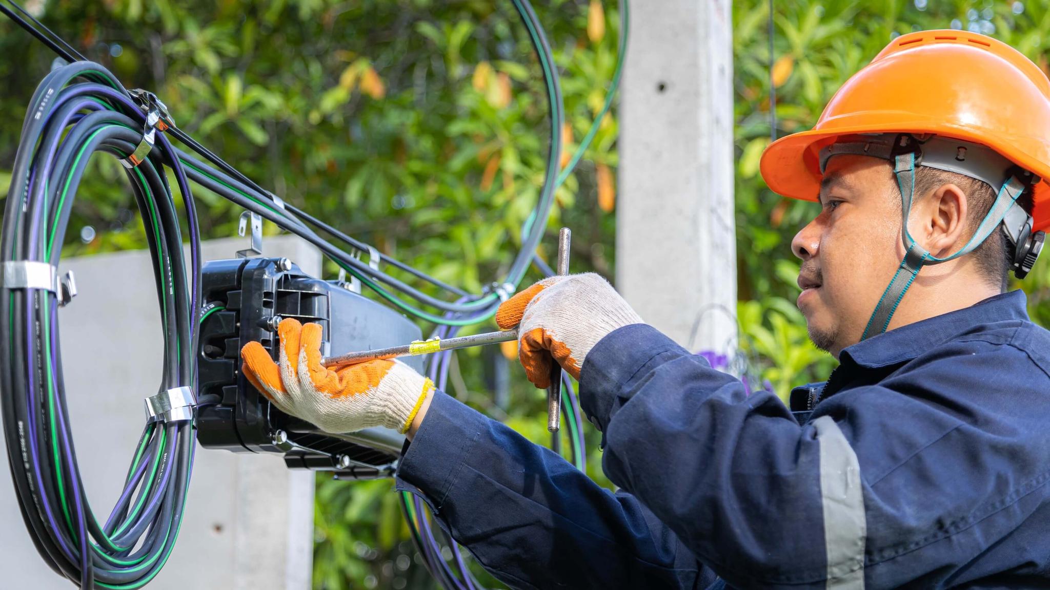 Technician checking fiber optic cables in internet splitter box