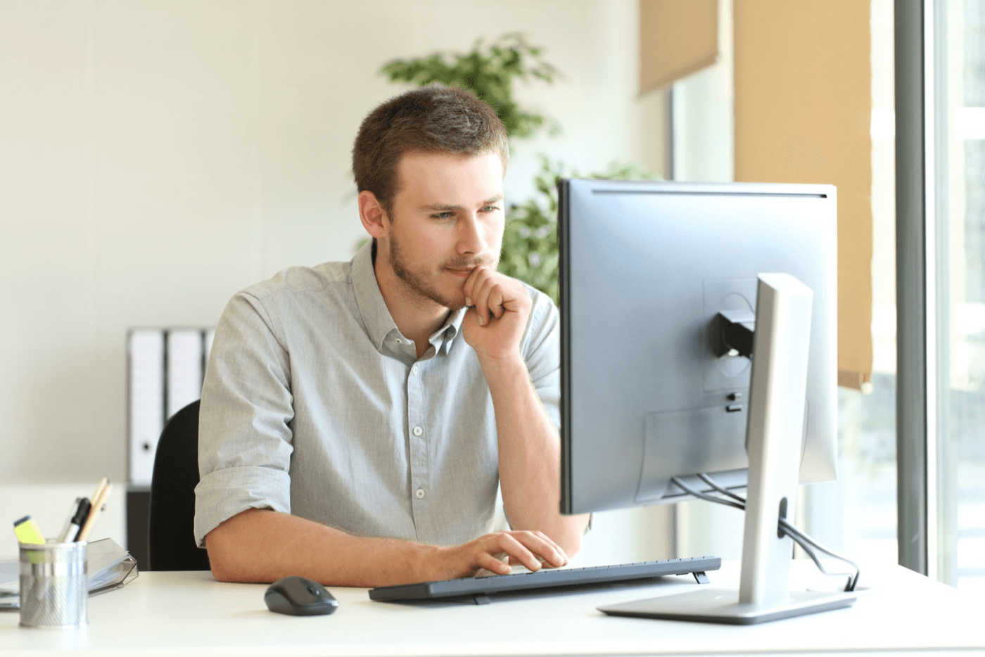 Man sits at desktop with pondering look on his face