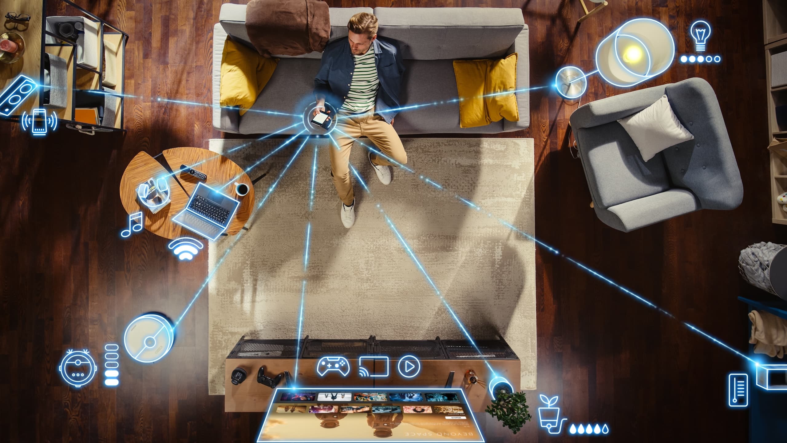 Man on couch holds phone that connects to other smart devices via Wi-Fi